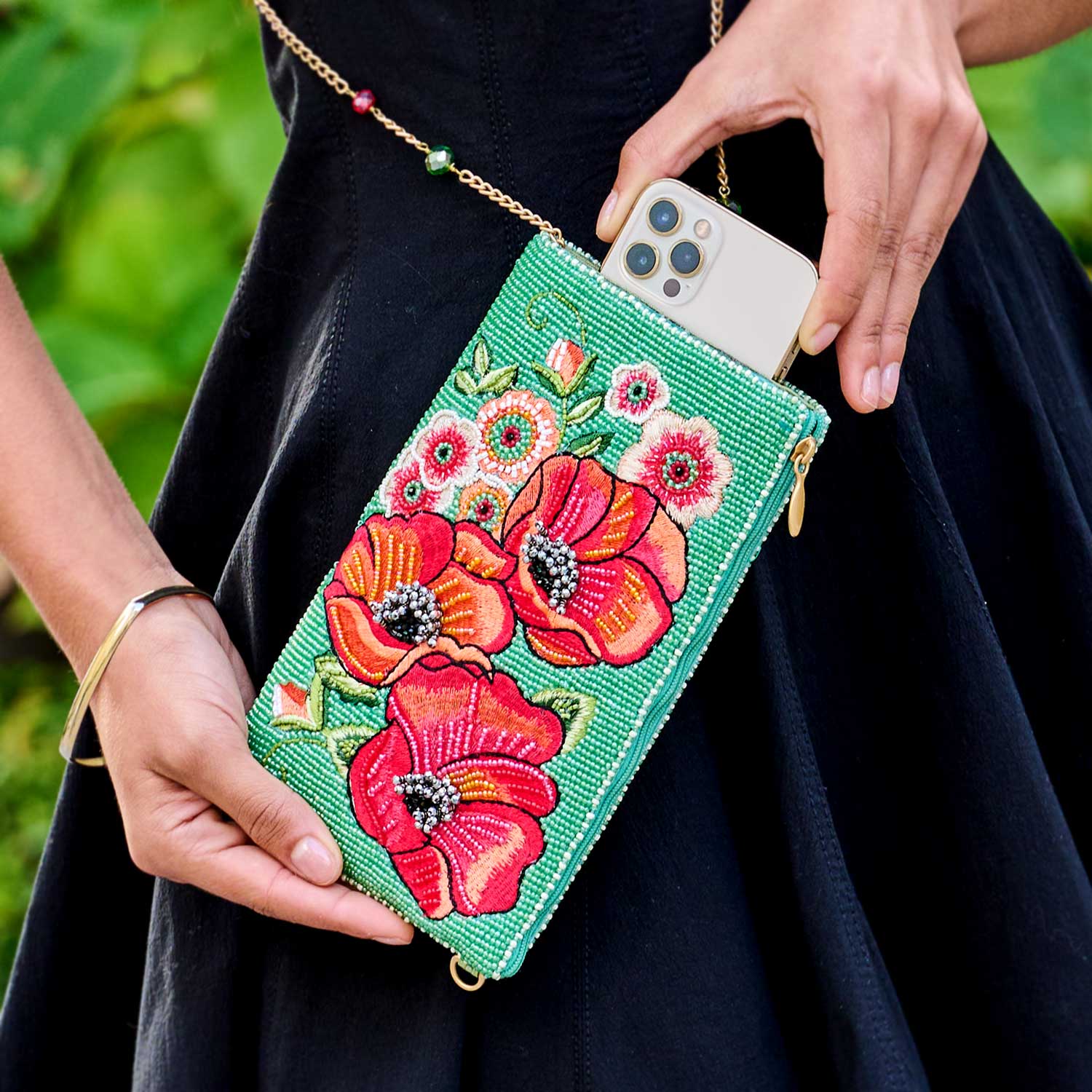 model putting a phone into Poppy Field Beaded Floral Crossbody Phone Bag purse